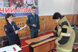 Людмила Кулаева  главный судья на олимпиаде школьников по ОБЗР при выполнении задания № 5 «Надевание боевой одежды пожарного».